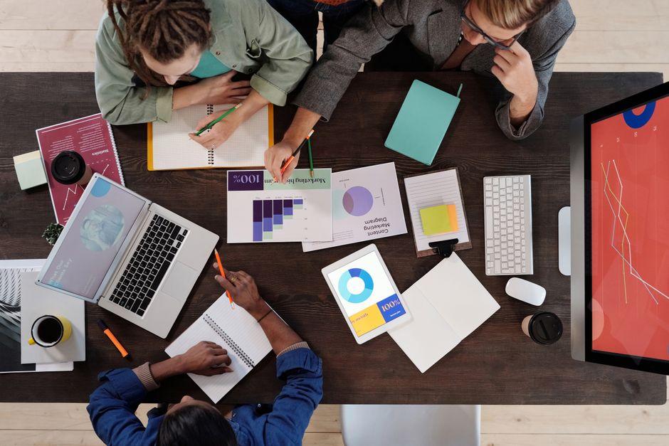 Vue aérienne d'une équipe diversifiée collaborant sur un projet dans un bureau moderne